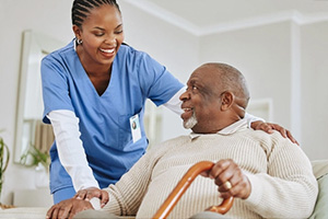an African American nurse helping an elderly gentleman who's holding his cane