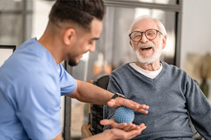 A rehab therapist helping an elderly gentleman in the rehab gym