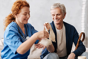 A wound care nurse helping an elderly woman with her bandages