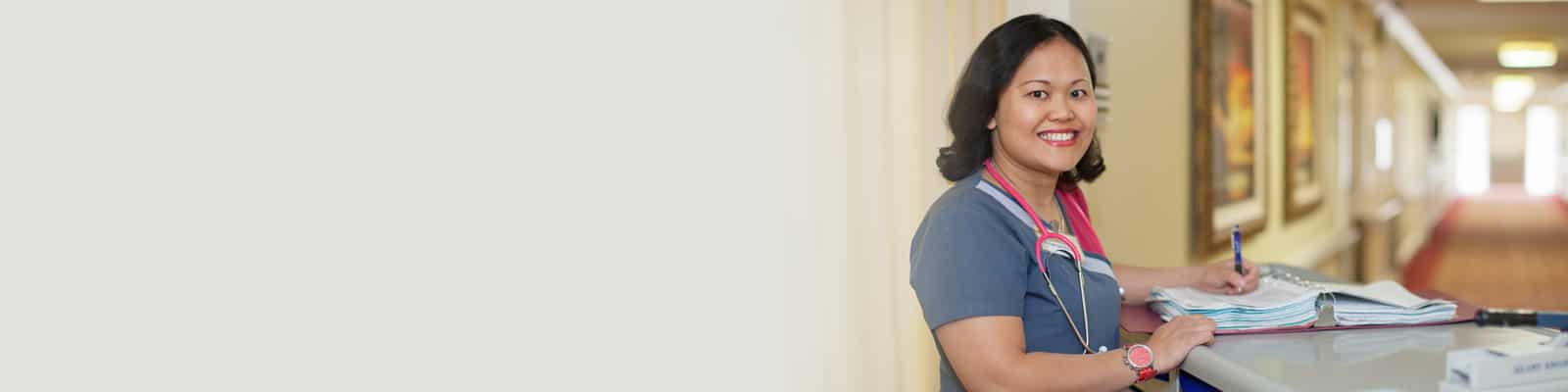 A nurse standing at a nurse's cart in the hallway at Redlands Healthcare Center