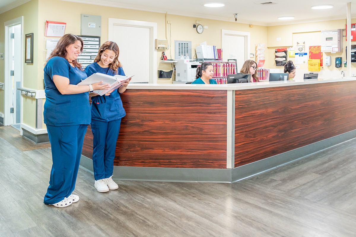 Nurses standing and sitting at a desk at Redlands Healthcare Center