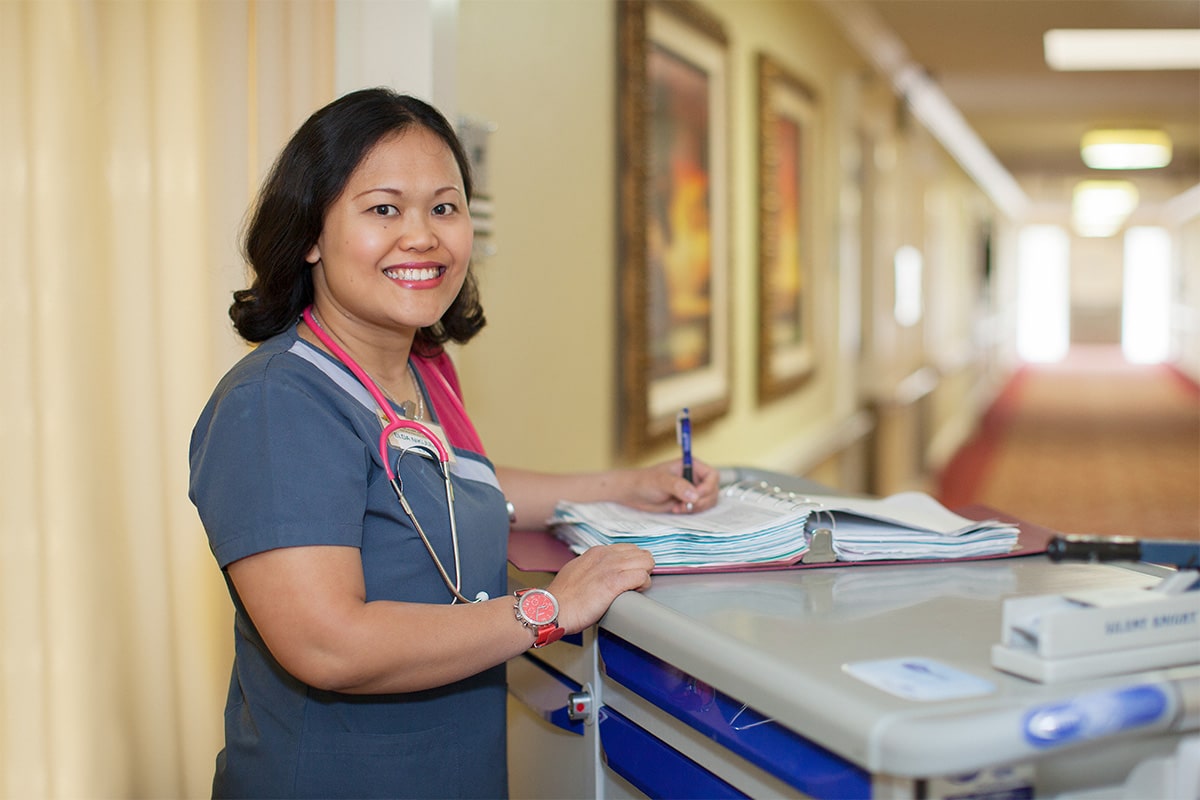 A nurse filling out paperwork at a desk at Redlands Healthcare Center