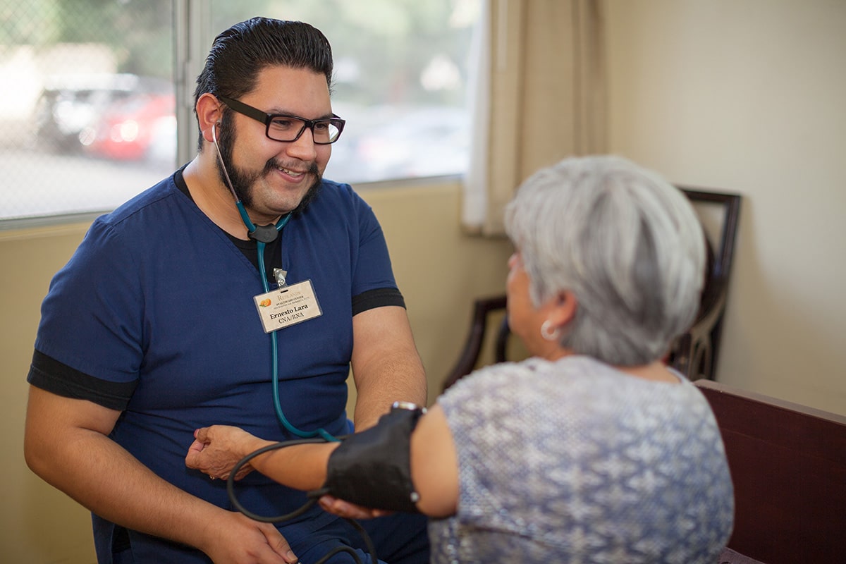 A nurse taking a patients blood pressure at Redlands healthcare Center