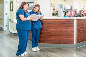 two nurses at the nurses' station at the Redlands Healthcare facility