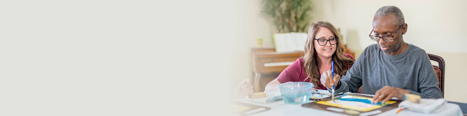 a caregiver helping a resident paint at the Redlands Healthcare facility